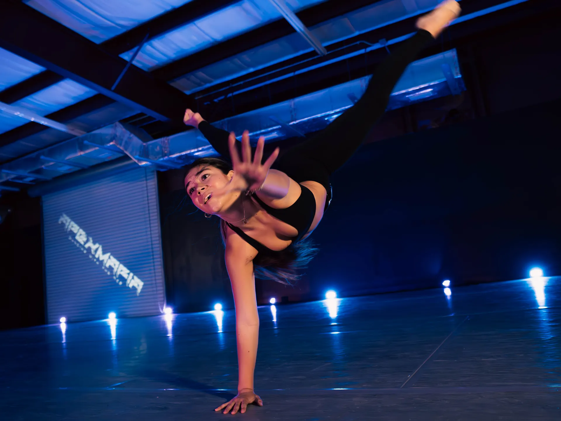 Dancer mid movement under blue stage light at an Apex Mafia intensive in Pensacola