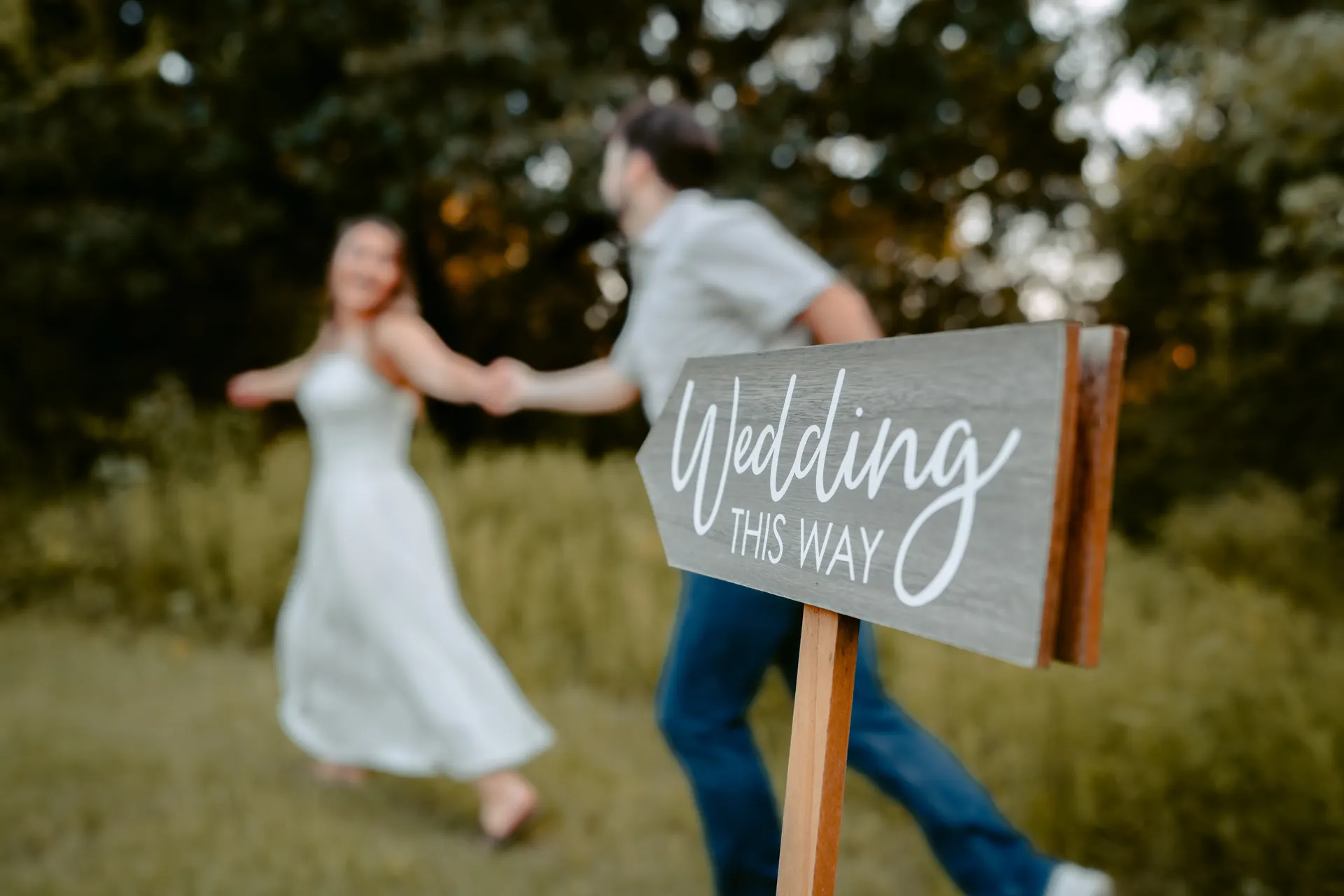 Engagement session at a Texas wedding venue, couple beside a hand lettered Wedding This Way sign at golden hour